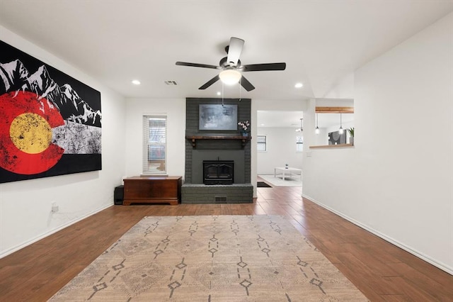 living room featuring hardwood / wood-style flooring, ceiling fan, and a fireplace