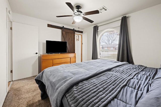 bedroom with a barn door, carpet floors, and ceiling fan