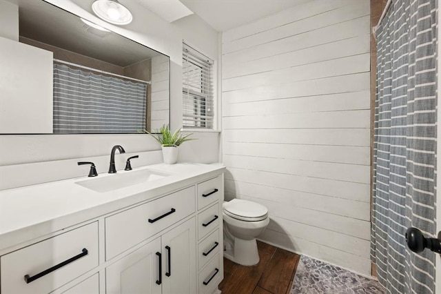 bathroom with hardwood / wood-style flooring, wooden walls, vanity, and toilet