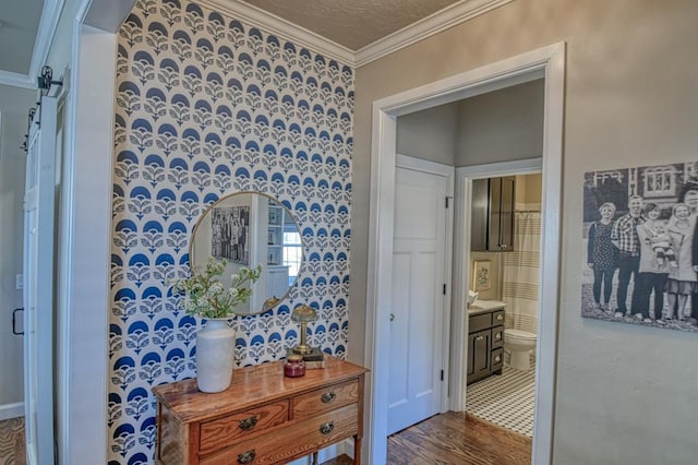 corridor with ornamental molding, hardwood / wood-style floors, and a textured ceiling