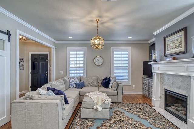 living room with ornamental molding, wood-type flooring, a barn door, and a high end fireplace