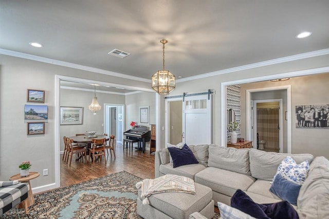 living room with ornamental molding, a barn door, and dark hardwood / wood-style floors