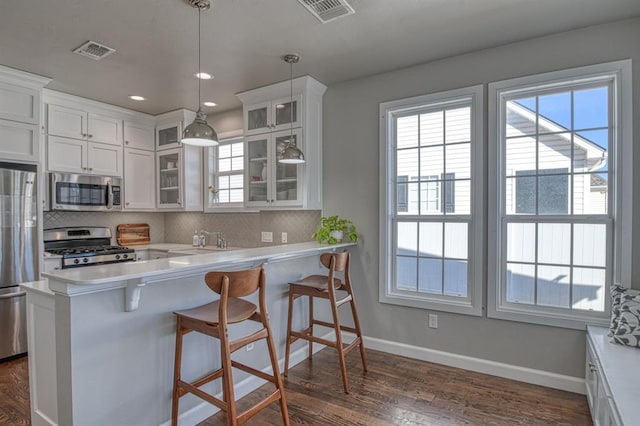 kitchen with stainless steel appliances, a breakfast bar area, pendant lighting, and white cabinets