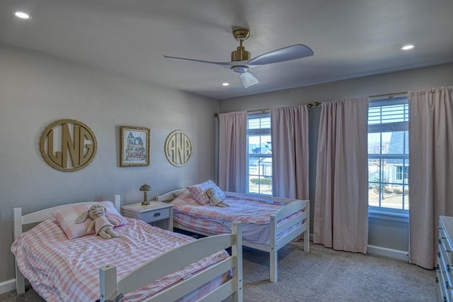 carpeted bedroom featuring multiple windows and ceiling fan