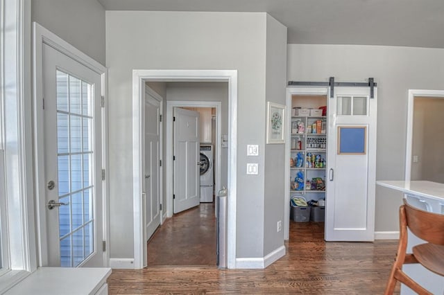 interior space featuring dark wood-type flooring, a barn door, and washer / dryer