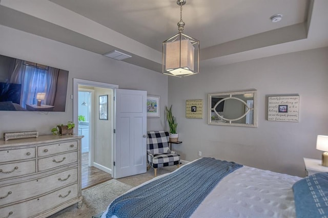 bedroom with light hardwood / wood-style flooring and a raised ceiling