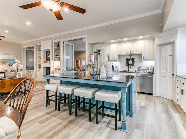 kitchen featuring white cabinetry, appliances with stainless steel finishes, a kitchen bar, and light wood-type flooring