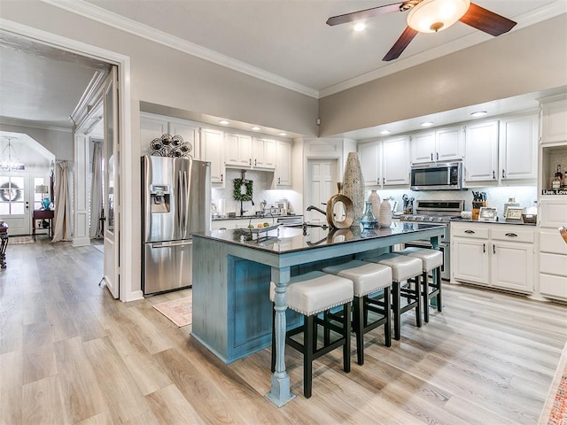 kitchen featuring a center island with sink, a breakfast bar, white cabinets, and appliances with stainless steel finishes