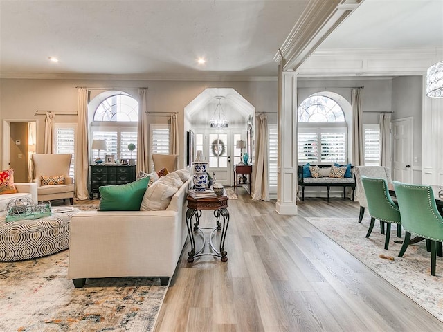 living room featuring an inviting chandelier, plenty of natural light, decorative columns, and light hardwood / wood-style flooring