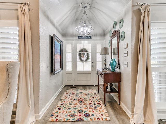 entryway with vaulted ceiling, a chandelier, and light hardwood / wood-style flooring