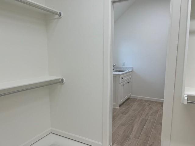 walk in closet with sink and light hardwood / wood-style floors