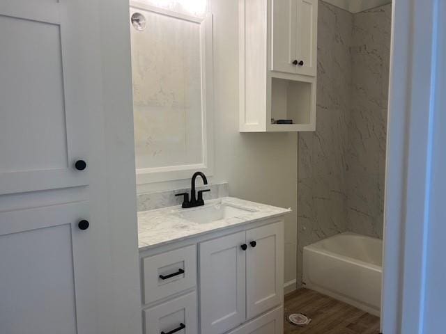 bathroom featuring wood-type flooring, bathing tub / shower combination, and vanity