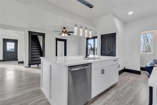 kitchen with pendant lighting, sink, a kitchen island with sink, white cabinets, and stainless steel dishwasher