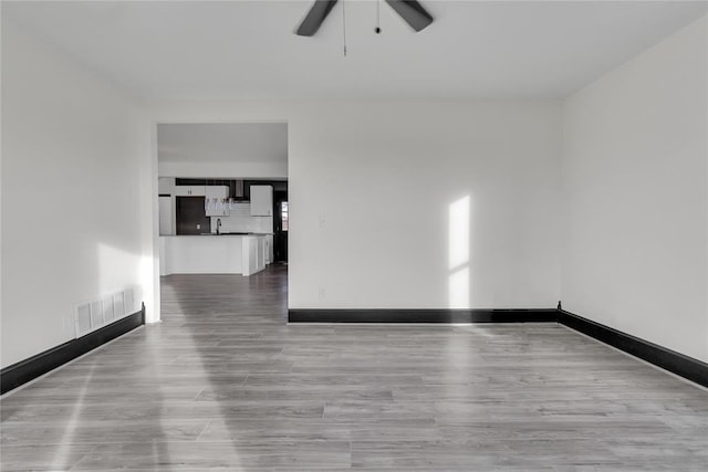 empty room with ceiling fan and light hardwood / wood-style flooring