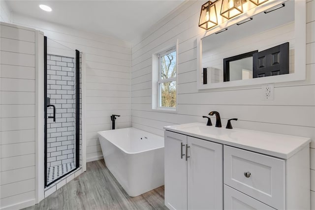 bathroom featuring vanity, wood-type flooring, and separate shower and tub