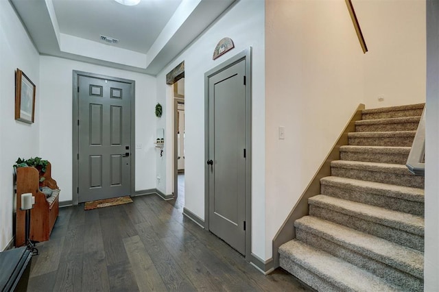 foyer with a tray ceiling and dark hardwood / wood-style flooring