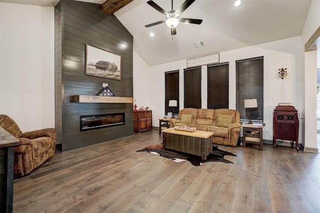 living room with high vaulted ceiling, dark hardwood / wood-style flooring, beamed ceiling, ceiling fan, and a fireplace