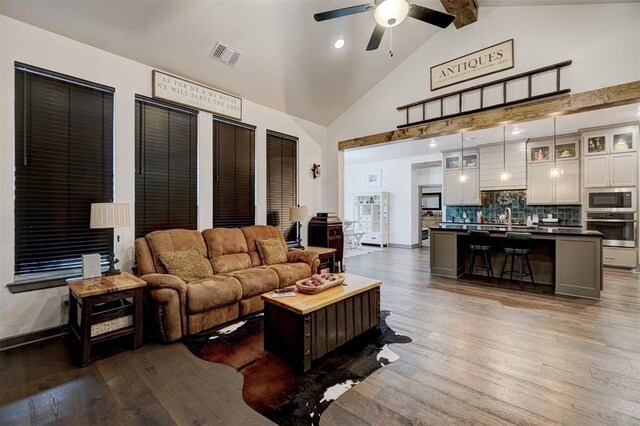 living room featuring high vaulted ceiling, beamed ceiling, sink, dark hardwood / wood-style flooring, and ceiling fan