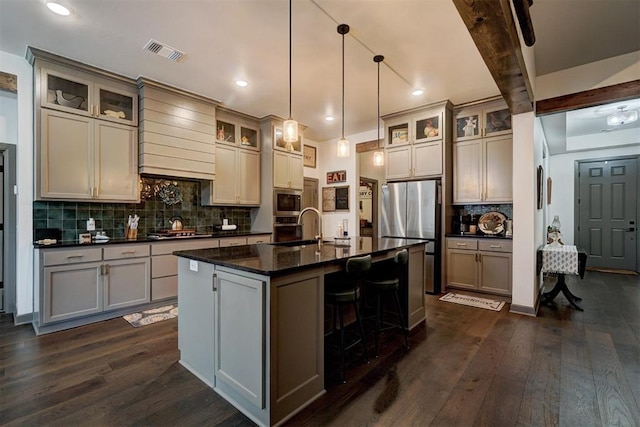 kitchen featuring dark hardwood / wood-style flooring, an island with sink, custom range hood, pendant lighting, and stainless steel appliances