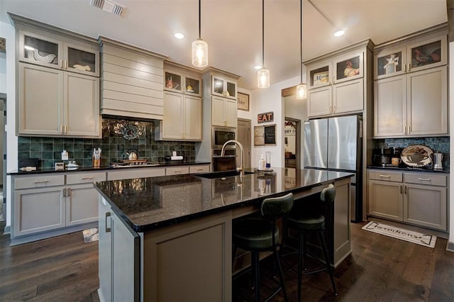 kitchen featuring a kitchen island with sink, sink, decorative light fixtures, and stainless steel appliances