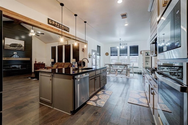 kitchen featuring sink, a kitchen island with sink, built in microwave, decorative light fixtures, and stainless steel dishwasher