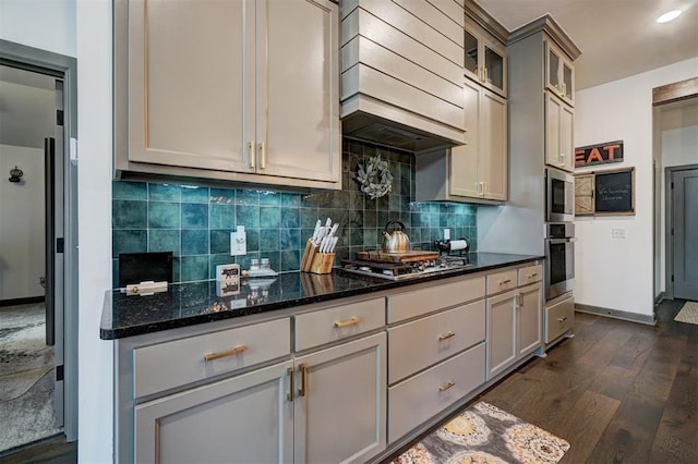 kitchen featuring gray cabinets, premium range hood, appliances with stainless steel finishes, backsplash, and dark stone counters