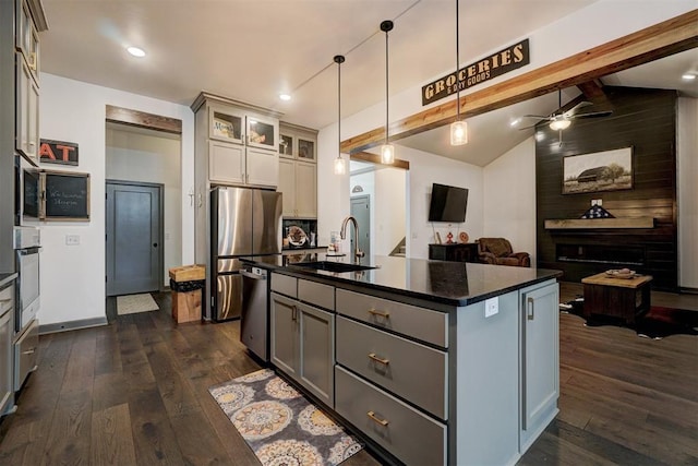 kitchen featuring a center island with sink, hanging light fixtures, sink, and gray cabinetry