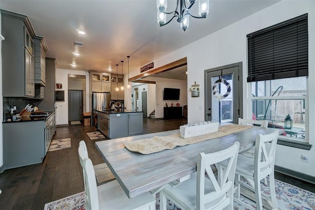 dining area with dark hardwood / wood-style floors, sink, and a notable chandelier