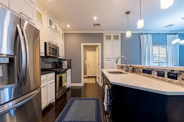 kitchen featuring sink, appliances with stainless steel finishes, white cabinetry, an island with sink, and decorative light fixtures