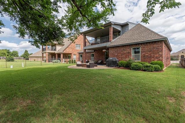 rear view of house featuring a balcony, a yard, and a patio