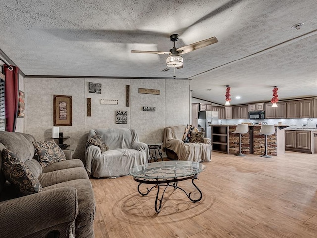 living room featuring crown molding, ceiling fan, light wood-style flooring, and a textured ceiling
