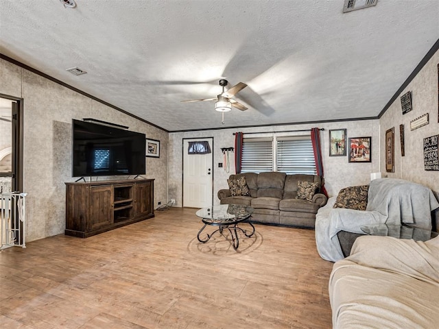 living room featuring crown molding, a textured ceiling, visible vents, and light wood-style floors