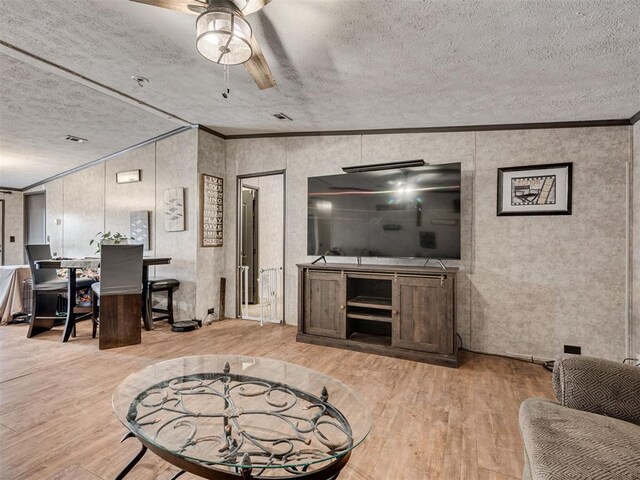 living area featuring light wood-style floors, crown molding, a textured ceiling, and ceiling fan
