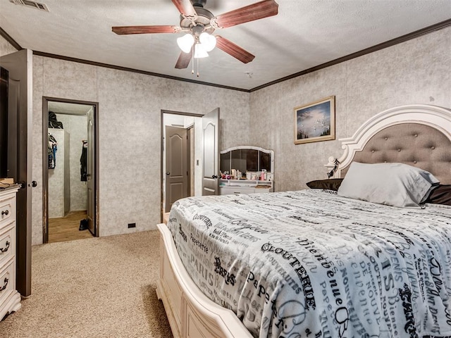 bedroom featuring light colored carpet, visible vents, ornamental molding, ceiling fan, and a textured ceiling