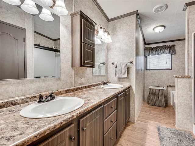 full bath with crown molding, visible vents, and a sink