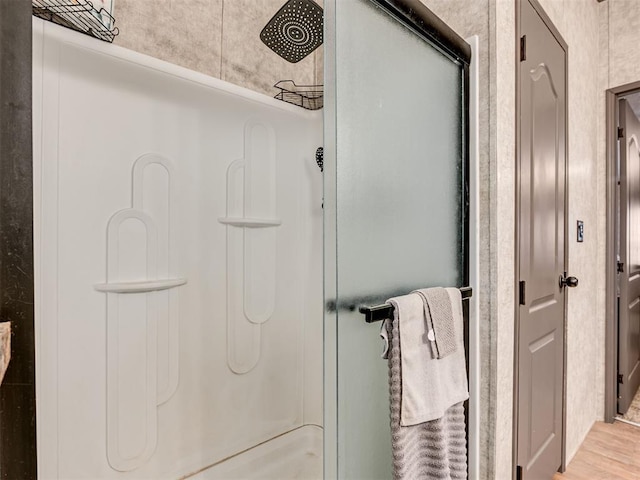 bathroom with a shower stall and wood finished floors