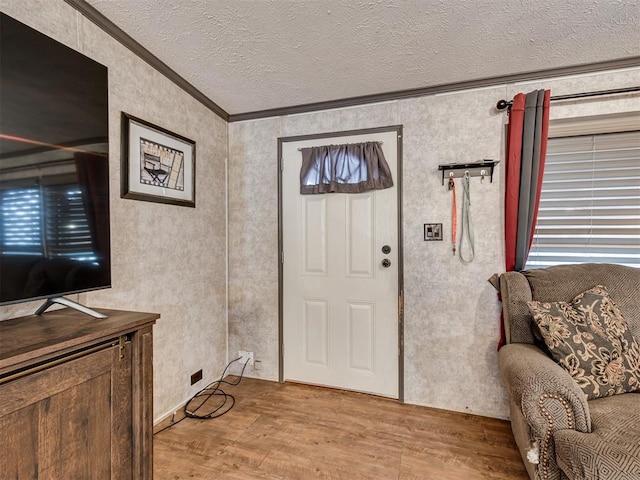 entrance foyer featuring crown molding, light wood-style flooring, and a textured ceiling