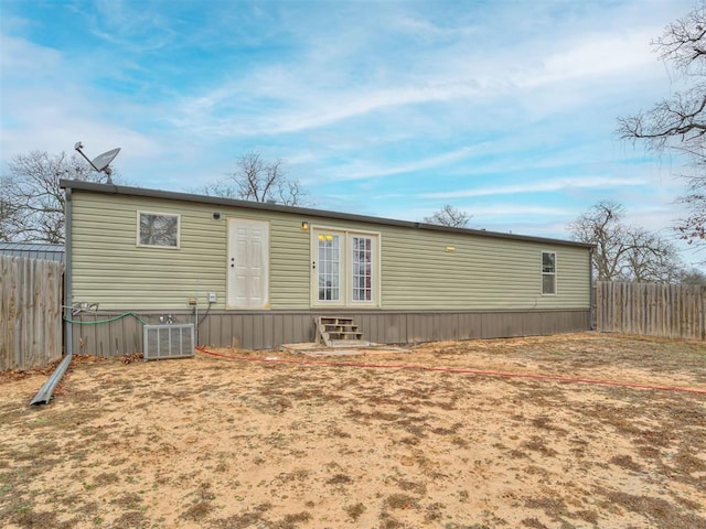 rear view of house featuring entry steps, fence, and cooling unit