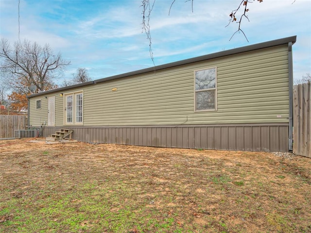view of property exterior featuring entry steps, a yard, and fence