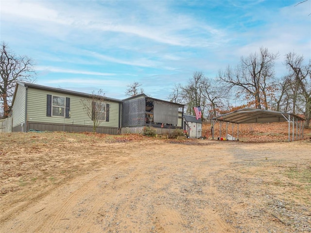 view of front facade featuring dirt driveway and a carport