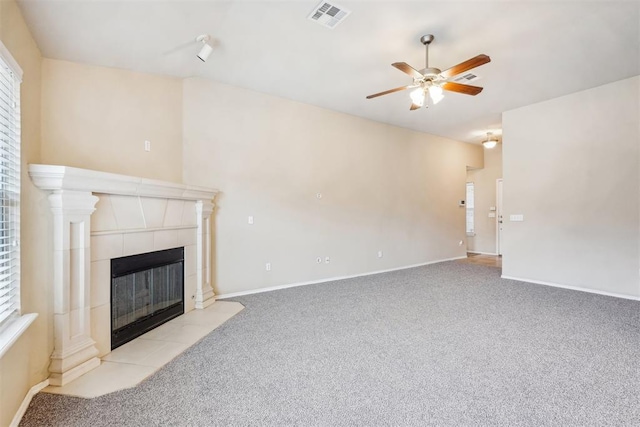 unfurnished living room with ceiling fan, a wealth of natural light, light carpet, and a fireplace