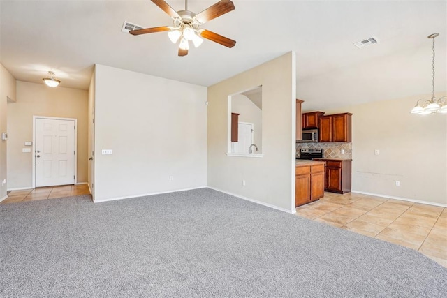 unfurnished living room featuring light carpet and ceiling fan with notable chandelier