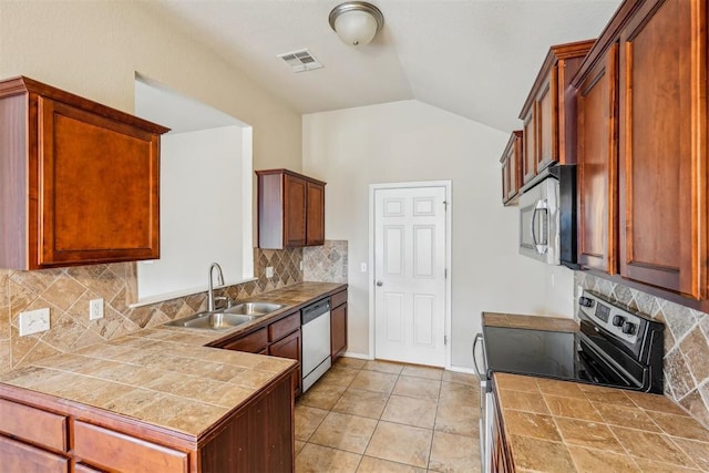 kitchen with stainless steel appliances, vaulted ceiling, sink, and tile countertops