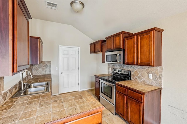 kitchen featuring lofted ceiling, sink, tasteful backsplash, and appliances with stainless steel finishes