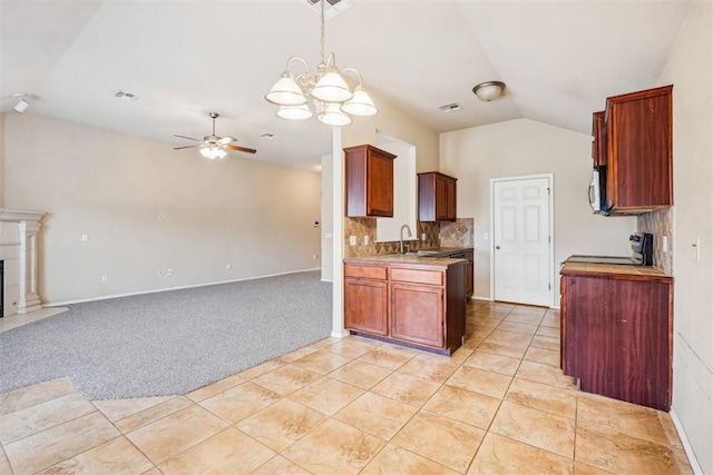 kitchen featuring sink, tasteful backsplash, light carpet, ceiling fan with notable chandelier, and vaulted ceiling