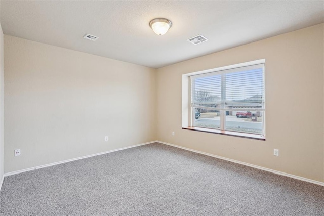 carpeted empty room featuring a textured ceiling