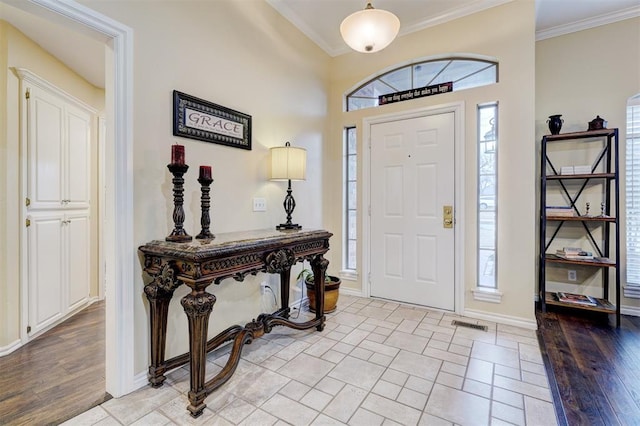 entrance foyer featuring crown molding and light hardwood / wood-style floors