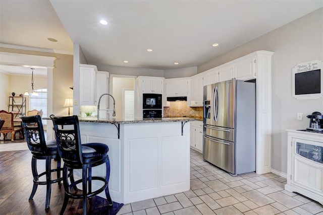 kitchen featuring stainless steel fridge with ice dispenser, black microwave, and white cabinets