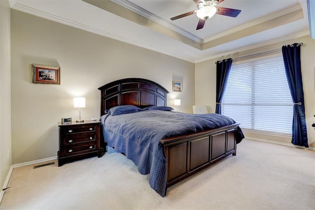 carpeted bedroom with a tray ceiling, ornamental molding, and ceiling fan