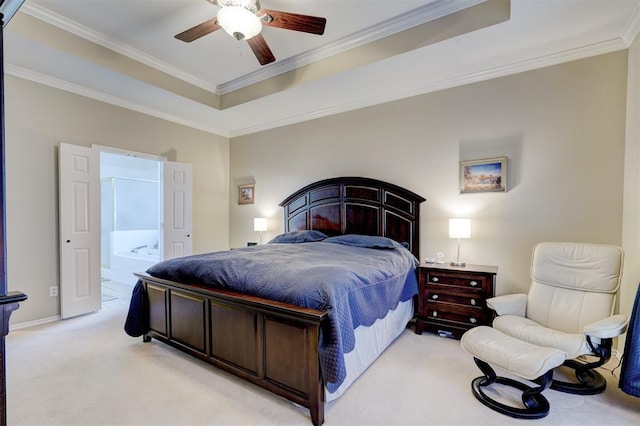 bedroom with crown molding, ensuite bath, ceiling fan, a tray ceiling, and light colored carpet